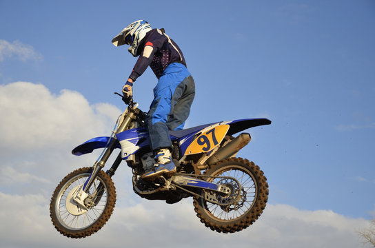 Motocross rider on flying through the air against the sky