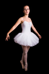 Naklejka premium Teen girl ballet dancer standing in white tutu on black backgrou