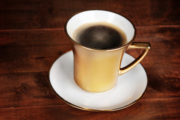 golden cup of coffee on wooden table