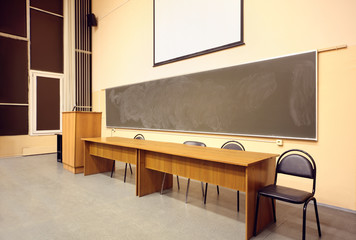 Large classroom, big blackboard, wooden table and black chairs