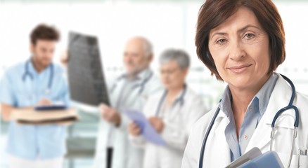 Senior female doctor medical team in background