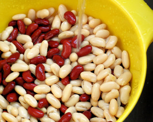 Red and white kidney beans being rinsed under water
