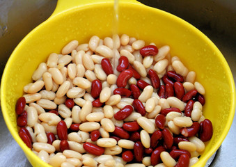 Red and white kidney beans being rinsed under water