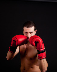Fototapeta na wymiar Man with boxing gloves on black background