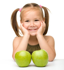 Little girl with two green apples