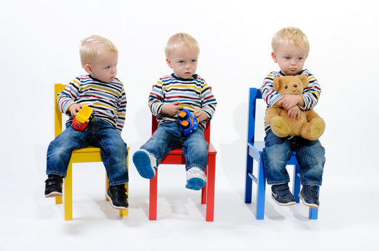 Drillinge auf bunten Kindersesseln