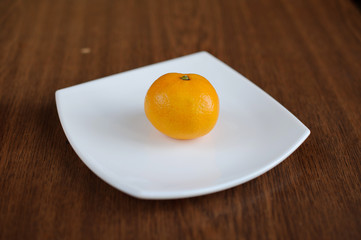 Ripe tangerine on white plate