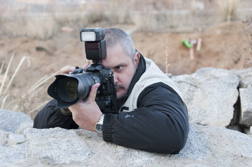 Fotógrafo a cubiero tras unas piedras.