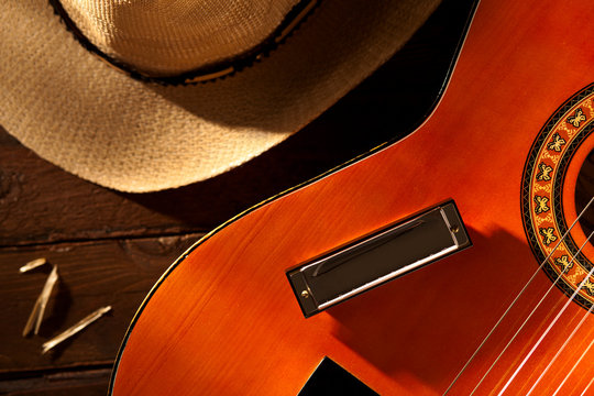 Harmonica on Guitar with Cowboy Hat on Wood