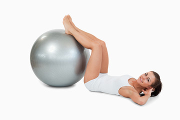Fototapeta na wymiar Young woman developing her abs with a ball
