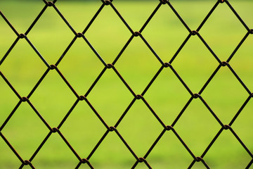 Fototapeta premium Closeup detail of chain link fence with green grass background