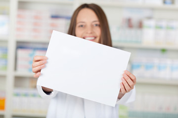 lächelnde apothekerin zeigt weißes schild