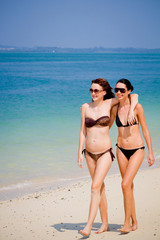 Two young and attractive women walking on the beach