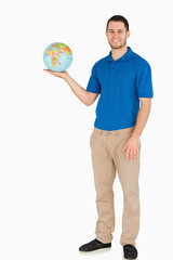 Fototapeta premium Smiling young salesman holding globe in his palm