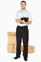 Smiling young post employee with parcels and clipboard