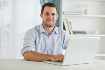 Fototapeta premium Biznesmen z podwiniętymi rękawami na swoim laptopie w swoim homeoffi