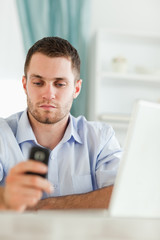 Fototapeta premium Businessman texting on his cellphone sitting behind his desk