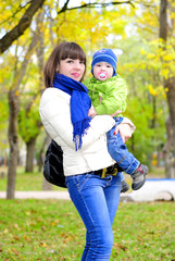 Fototapeta premium Маленький мальчик у мамы на руках осенью