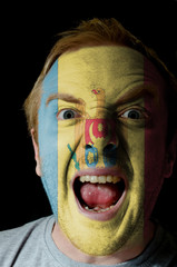Face of crazy angry man painted in colors of moldova flag