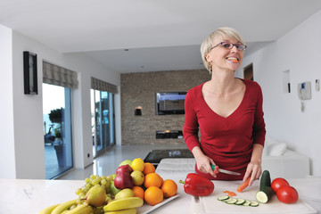 Obraz premium happy beautiful blonde woman prepare food in the kitchen