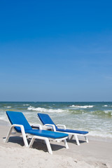 Fototapeta na wymiar Two sun beach chairs on shore near ocean