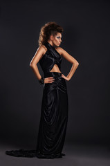 Fototapeta premium Woman in black long dress over dark background