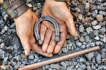 Detail of dirty hands holding horseshoe - blacksmith