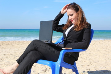 Business woman sits and works, near the ocean
