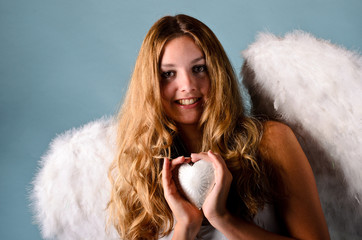 Christmas: Smiling angel with a silver heart and blue background