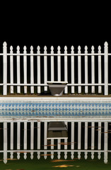 A Swimming Pool and White Picket Fence at Night