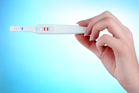 pregnancy test in hand on blue background