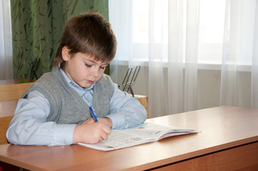 Schoolboy at his desk in the classroom makes the lessons