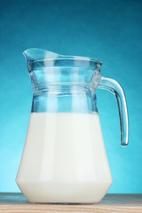 Tasty milk in jug on blue background
