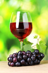 Ripe grapes and  glass of wine on  green background