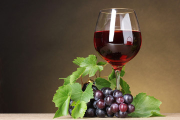 Glass of wine and grapes on yellow background