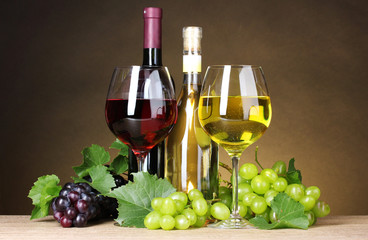 Glasses of wine, bottles and grapes on yellow background