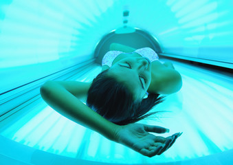 Beautiful young woman tanning in solarium
