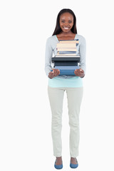 Smiling young woman carrying a stack of books