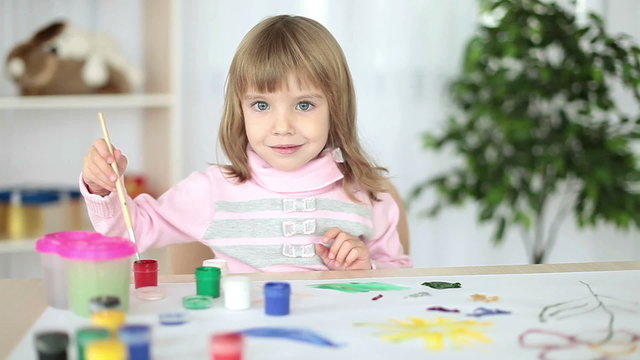 Girl learns to paint with gouache looking at camera