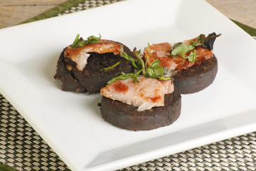 three pieced of grilled black pudding bacon and garnish