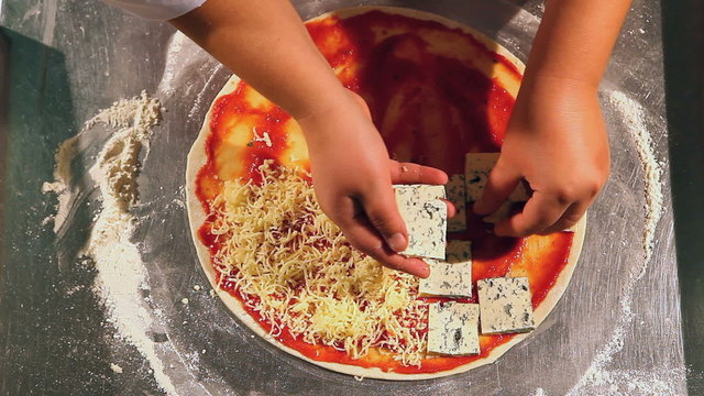 Chef puts cheese on pizza