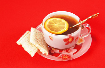 Cup of black tea with a lemon on a red cloth