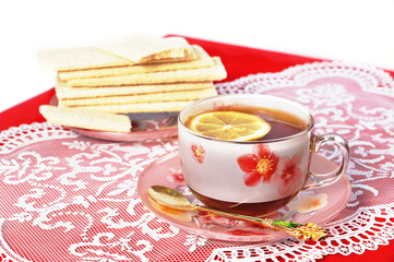 Cup of black tea with a lemon on a red cloth