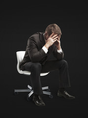 Young businessman sitting on chair with head down