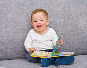 The one-year-old kid sits with the book