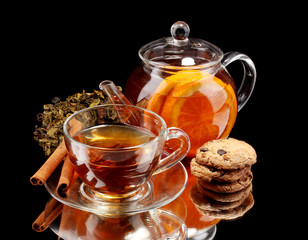 Glass teapot and cup with black fruit tea and cookies isolated