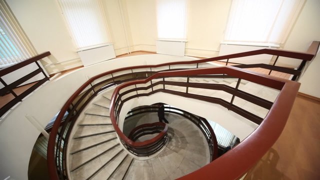 Man walk down by marble circular stairs, view from above