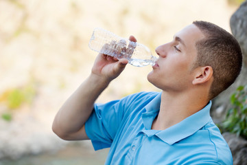 Young man drinking water outside