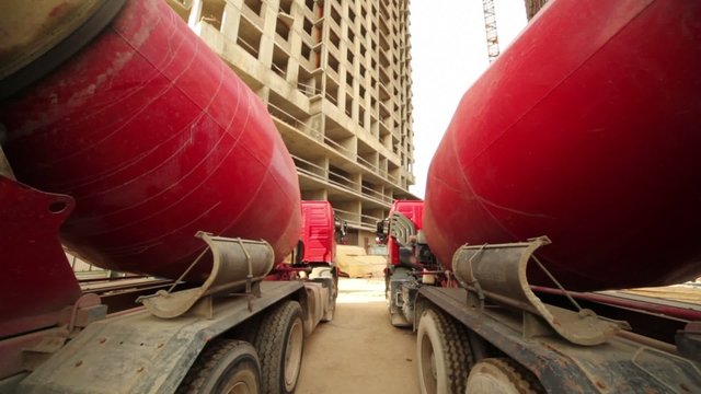 Between two concrete mixer near unfinished tall house