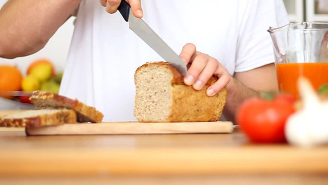 Male hands slicing bread, slow motion